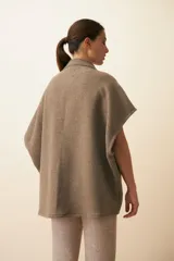 Chaleco color crema de lana sin teñir, corte recto, con cuello y solapa pronunciadas, broches a presión y bolsillos ojal.