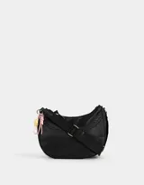Bandolera hobo negra de tela deportiva con correa regulable, cierre superior, bolsillo frontal y charm lateral decorativo.