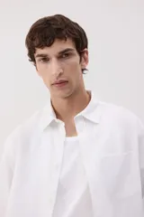 Camisa blanca de lino y algodón con cuello inglés, tapeta clásica y canesú en la espalda. Modelo de manga larga con bolsillo superior abierto, cierre ajustable de botón en los puños y tapeta con botón. Bajo redondeado. Corte estándar.