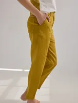 Pantalón largo de lino color marrón, con corte cigarette, tiro alto, bolsillos laterales y traseros con pespuntes a la vista, y etiqueta de cuero con logo en la cintura.