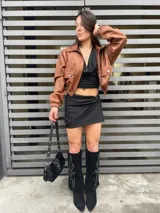 Minifalda negra con brillos, corte ajustado y detalle de nudo en la parte delantera.