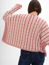 Sweater tejido de punto color crudo con rayas verticales negras y cuello redondo. Tiene un corte crop y un diseño con trenzas.