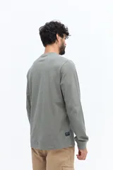 Remera de manga larga color negro, con escote redondo y un pequeño logo circular estampado en el pecho.