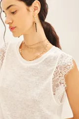 Musculosa blanca de lino con detalle de encaje en mangas y cuello. Tiene bordado de alas en el bajo.