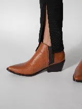 Botín de cuero color marrón claro, con elástico negro en los laterales, punta fina y taco cuadrado bajo color negro.