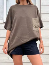 Remera holgada color naranja quemado, con cuello redondo y mangas raglán cortas. Posee un bolsillo de parche en el pecho, aparentemente de un material diferente o con textura contrastante.