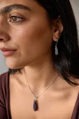 Aros colgantes de acero quirúrgico hipoalergénico con dije de piedra natural en forma de gota color azul oscuro.