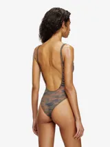 Traje de baño entero de una pieza, color camuflado en tonos tierra (naranja quemado, verde oliva y azul oscuro), con escote redondo y tirantes finos. Presenta un pequeño recorte con detalle metálico en el centro del escote.