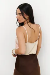 Musculosa de tirantes delgados con diseño bicolor: la parte superior es de color crema y la parte inferior es de color rosado pálido, ambas con acabado satinado.