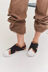 Zapatillas slip-on doradas con puntera redondeada y banda elástica ancha en color beige.