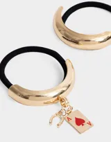 Set de dos gomitas de pelo elásticas negras, una con aplique metálico dorado en forma de medialuna y otra con aplique metálico dorado en forma de medialuna con dije colgante de herradura y naipe de as de corazones.