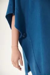 Poncho azul con cuello redondo y terminación desflecada.