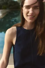 Vestido corto sin mangas en denim azul, con escote redondo y cierre oculto en la espalda. Costura visible en la cadera y pollera acampanada con nesgas para dar vuelo.