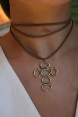 Gargantilla marrón de cuero con dije de cruz de bronce formada por aros.