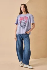 Remera blanca de algodón con estampado de un tucán, palmeras y la frase 'Tropical Bliss' en tonos naranja y rosa.