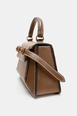 Bolso de mano tipo satchel color marrón, con costuras contrastantes en blanco. Presenta un asa superior curva, solapa frontal con dos hebillas metálicas decorativas y correa ajustable para llevar al hombro.