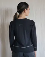 Remera negra de mangas largas con cuello en V y detalles de pespuntes blancos.