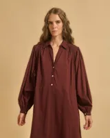 Vestido largo color borgoña, con mangas abullonadas, hombros fruncidos, botones en el pecho y cuello camisero con escote en V.