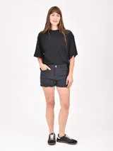 Short de jean color crudo, tiro alto, con bolsillos delanteros y traseros, y ruedo desflecado.