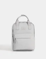 Mochila gris de tela deportiva con correas regulables, manijas superiores con broche, acceso con cierre superior y puller de cuerina, bolsillo frontal con cierre y puller de cuerina, y tag de goma.