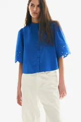 Blusa azul eléctrico de algodón con cuello mao, botones frontales, manga 3/4 abullonada con bordado calado y puños festoneados.