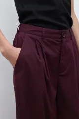 Pantalón de mujer color beige, tiro alto, con pliegues (pinzas) frontales y corte ancho y recto en las piernas.