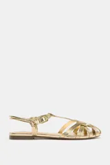 Sandalias planas doradas tipo cangrejeras con tiras finas entrecruzadas y cierre con hebilla ajustable en el tobillo.