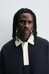 Polo negro de corte relaxed fit confeccionado en tejido con algodón. Cuello solapa con cierre frontal de botonadura. Manga larga. Bajo con aberturas laterales. Acabados en rib.