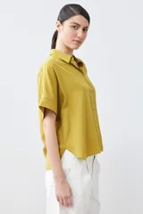 Camisa color pistacho de lyocell con cuello clásico, cierre frontal con botones y mangas cortas.