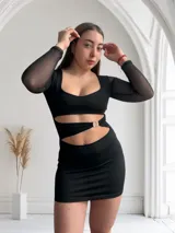 Minivestido negro con escote cuadrado, mangas largas de tul y aberturas en la cintura unidas por aros metálicos.