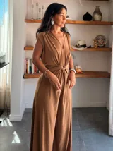 Mono largo color camel, sin mangas, con escote en V profundo y detalle de nudo cruzado en la cintura. El pantalón es de corte ancho y fluido.