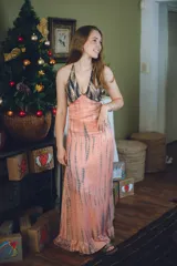 Vestido largo color marrón cobrizo con escote en V, cut outs laterales bajo el busto y breteles finos que se cruzan y atan en la espalda. Presenta un top con estampado abstracto en tonos marrones y dorados.