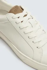 Zapatillas deportivas blancas con detalle de color marrón en el talón y suela con volumen.