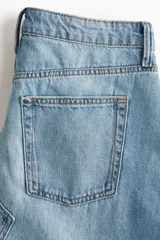 Pollera midi de denim celeste, de corte evasé, con tiro alto, cinco bolsillos y cierre frontal con botones.