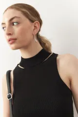 Musculosa roja de punto con cuello alto y pequeñas aberturas en los hombros.