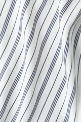 Blusa de manga larga a rayas verticales blancas y negras, con cuello clásico, escote en V y cierre frontal con botones. Puños con detalle de rayas horizontales y bajo redondeado.