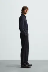 Camisa color beige de corte slim fit, confeccionada en tejido elástico que minimiza las arrugas. Tiene cuello italiano abierto, manga larga con puños abotonados y cierre frontal con botones.