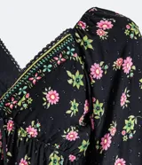 Vestido largo de viscosa negra con estampado floral en tonos rosa y verde. Tiene mangas largas abullonadas, escote en pico con detalle de puntilla y lazo frontal.