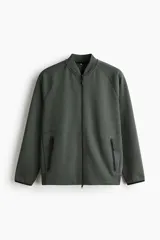 Campera bomber deportiva de tejido funcional color verde oscuro, con cuello elevado corto, cierre bidireccional y mangas raglán. Posee bolsillos delanteros con cierre y costuras selladas.