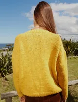 Sweater tejido de lana color amarillo con bordado de cigüeña en el frente y detalle floral en la manga.