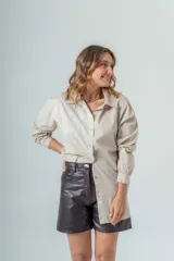 Camisa color beige de corte clásico, con cuello camisero, mangas largas con puños abotonados y cierre frontal con botones.