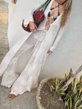 Saco largo de tejido de punto negro con diseño calado y acordonado en el frente, de manga larga.