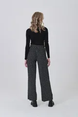 Pantalón de tiro alto, corte recto y largo, con estampado de lunares blancos sobre fondo negro.