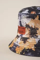 Gorro tipo bucket con estampado de hojas en tonos verde, amarillo y blanco.