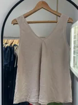 Musculosa color beige con escote en V pronunciado tanto en el frente como en la espalda. Presenta un corte holgado con un pliegue central en el busto.