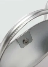 Bolso mini tipo bucket plateado, con asa de mano rígida y correa bandolera fina ajustable.