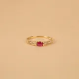 Anillo de oro amarillo 9k con un rubí central de forma ovalada y circonias engarzadas en los laterales.