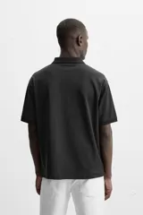 Polo gris de punto con cuello solapa y cierre frontal de cremallera. Corte regular fit, manga corta y acabados en rib.