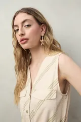 Mono enterito de algodón con rayas verticales color verde claro y beige, con cuello en V, sin mangas, con cierre frontal con botones y cinturón de lazo.