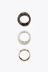 Set de tres pulseras rígidas: una dorada de metal y dos de resina, una color crema y otra marrón, ambas con tachas doradas.